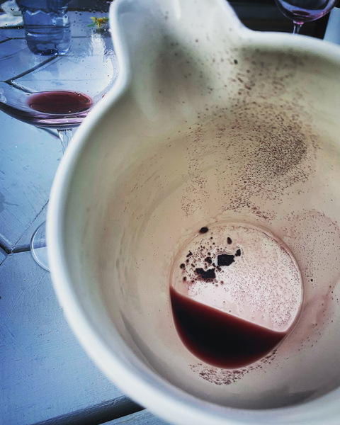 The coarse red wine tannin left behind in the bottom and sides of a white, ceramic pitcher